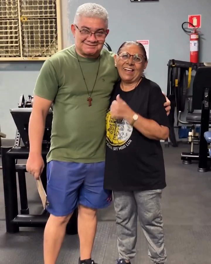 O casal abraçado na academia, sorrindo para a câmera.